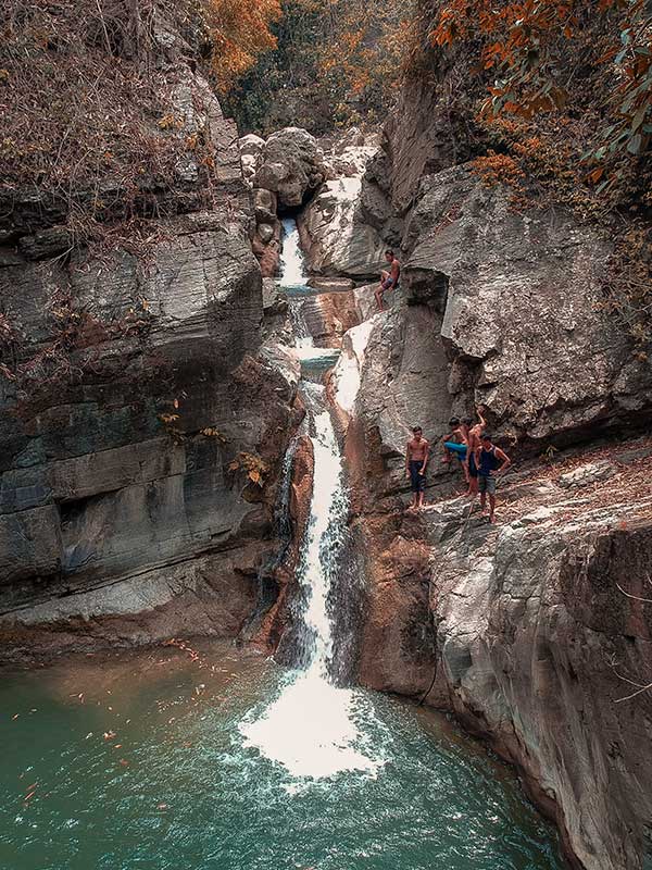 Local kids enjoy jumping the deep natural pool of Bobong Falls