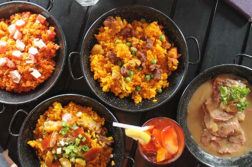 Aligue, pollo, and lechon paellas with a plate of lengua and a glass of Sangria