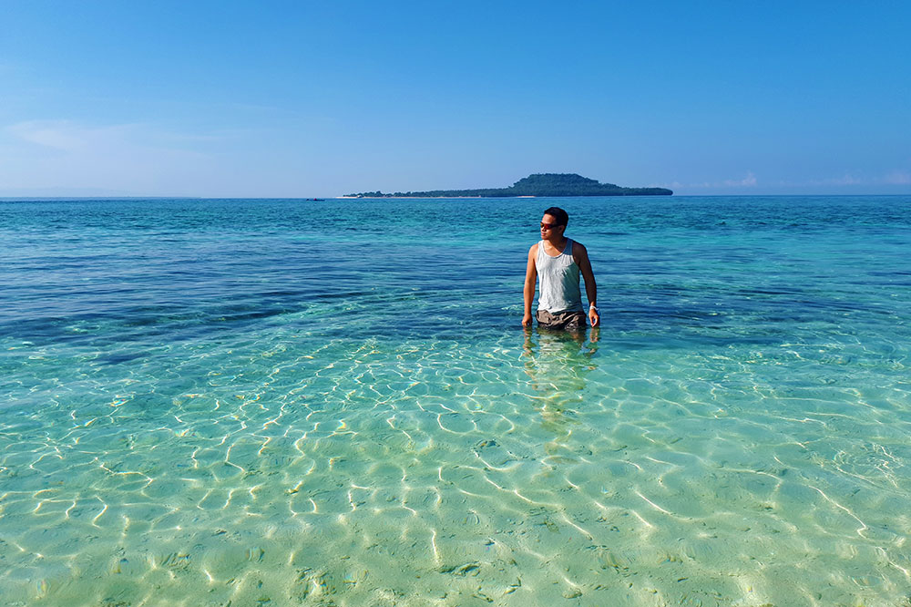 Ian Limpangog while wading the shallows of Mahaba Island with Himokilan Island in the background